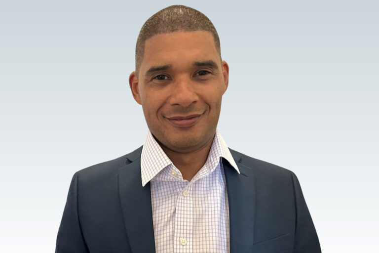 A headshot of a darker-skinned man with a buzzed haircut.