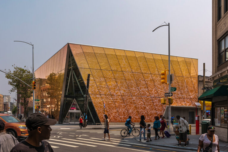 Exterior shot of Far Rockaway Library, a rectangular-cube-shaped building with bronze-like glass facade.