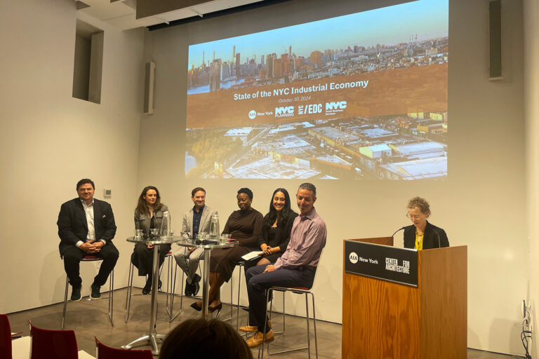 A group of panelists sit in front of a wall that is projecting an image of the NYC skyline, with text "State of the NYC Industrial Economy."