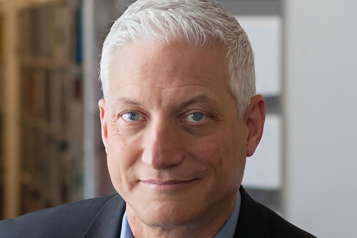 Headshot of an older white man with silver-white short hair and blue eyes.